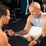 fitness & longevity instructor providing a weight training workout to a senior to enhance muscle after 50